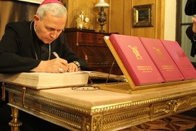 Bp Piotr Libera dokonuje wpisu do księgi pamiątkowej Towarzystwa Naukowego Płockiego