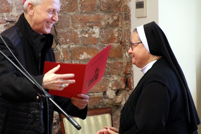 Siostra Aneta Krawczyk, pasjonistka, przyjmuje odznaczenie z rąk biskupa płockiego.